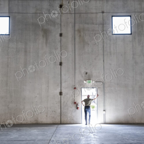 Worker standing silhouetted in doorway of new warehouse. Worker standing silhouetted in doorway of new warehouse.