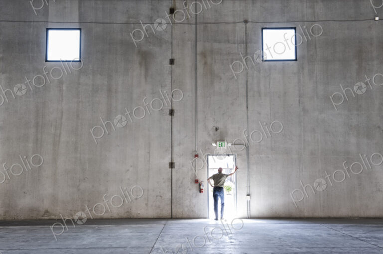 Worker standing silhouetted in doorway of new warehouse.