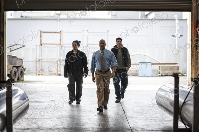 Workers and management person walking through a door into a sheet metal factory.