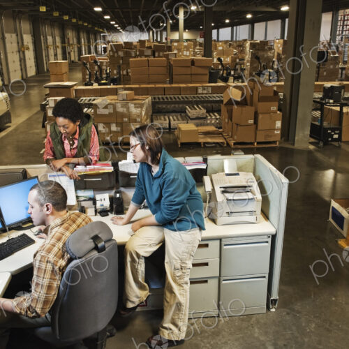 Workers studing a document on a computer at the front desk of a distribution warehouse. Workers studing a document on a computer at the front desk of a distribution warehouse.