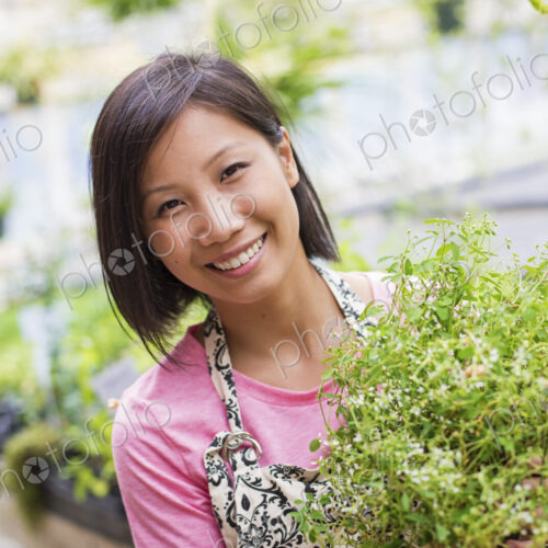 Working on an organic farm. A woman tending young plants in a glass house. Working on an organic farm. A woman tending young plants in a glass house.