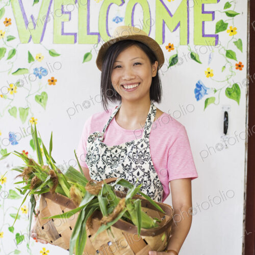 Working on an organic farm. A young Asian woman by the Welcome sign with a large… Working on an organic farm. A young Asian woman by the Welcome sign with a large…