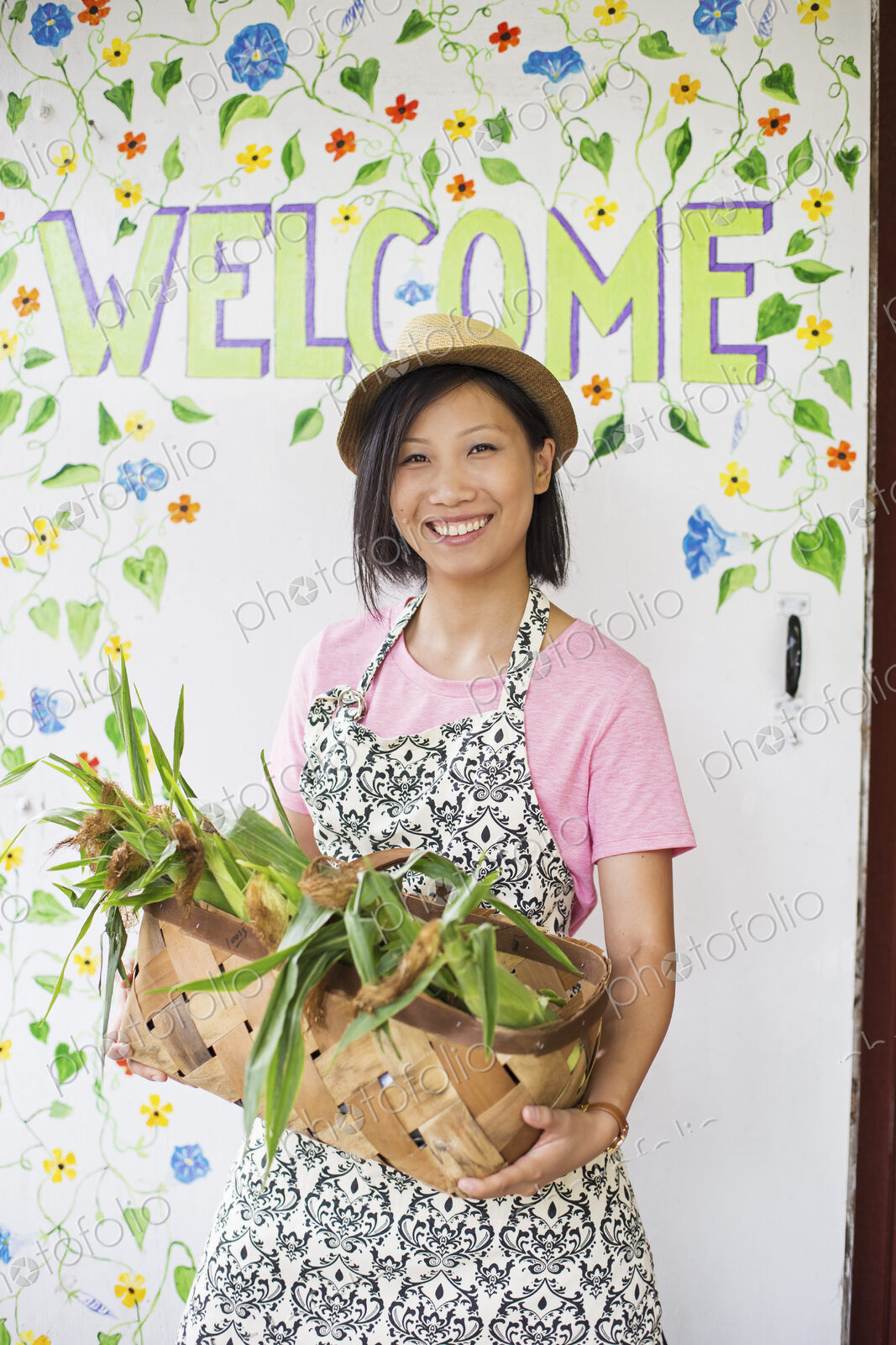 Working on an organic farm. A young Asian woman by the Welcome sign with a large…