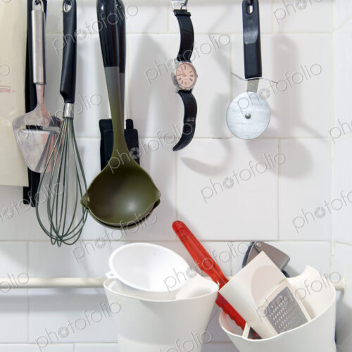 Wristwatch hanging on a rack amongst various kitchen tools