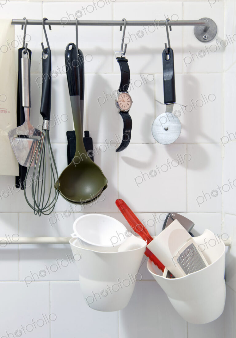 Wristwatch hanging on a rack amongst various kitchen tools