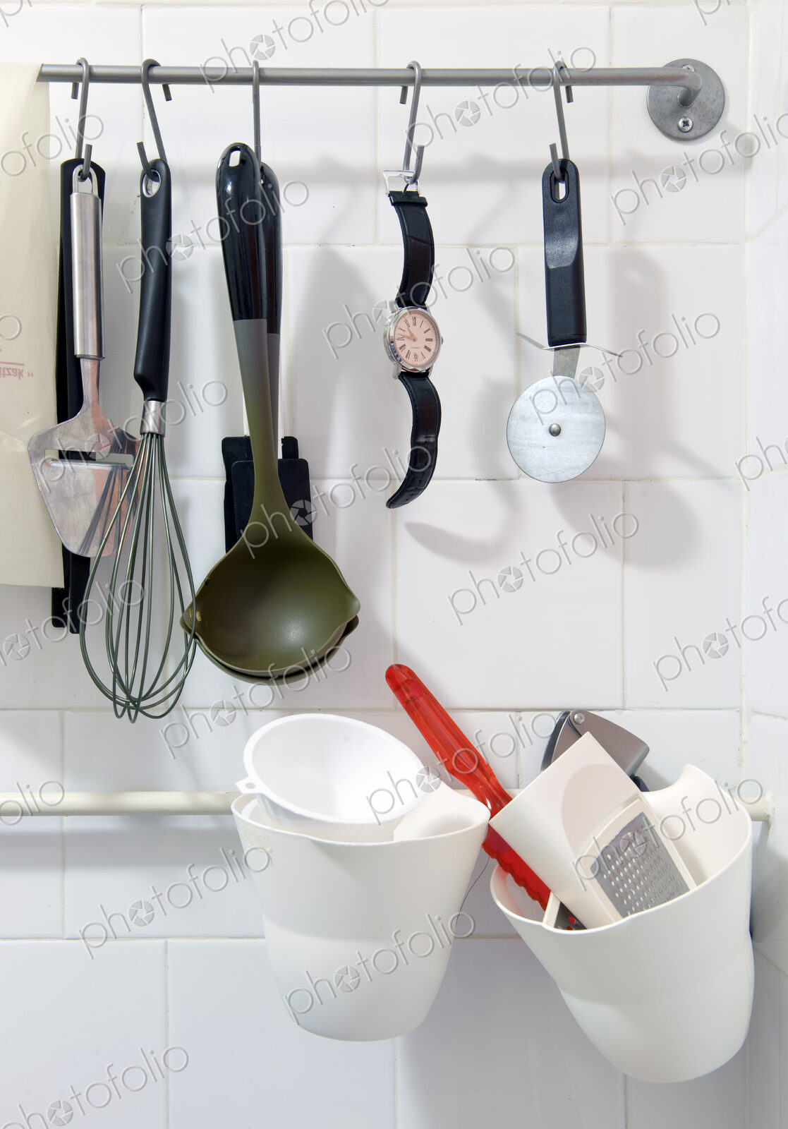 Wristwatch hanging on a rack amongst various kitchen tools