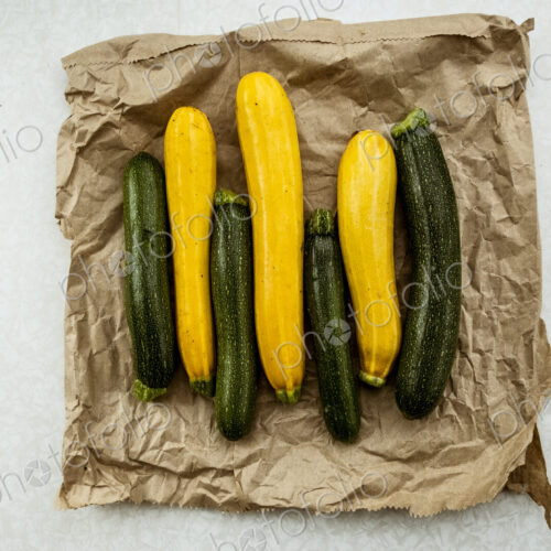 Yellow and green courgettes displayed on a crumpled brown paper bag. Yellow and green courgettes displayed on a crumpled brown paper bag.