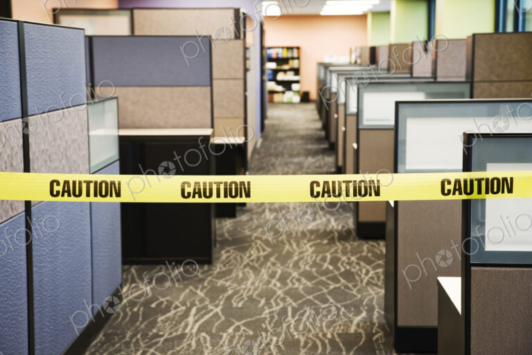 Yellow caution tape stretched between cubicles in an office space.