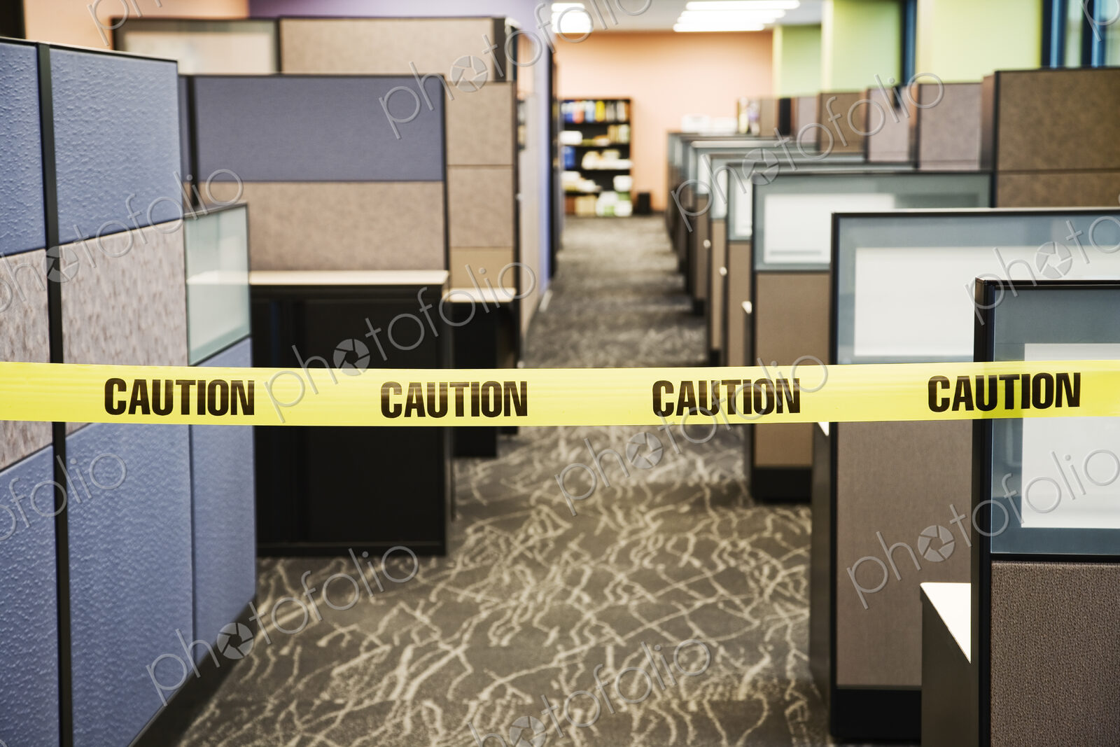 Yellow caution tape stretched between cubicles in an office space.
