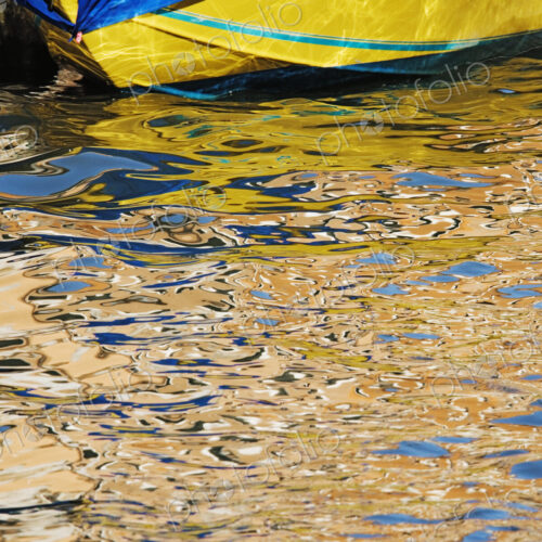 Yellow moored boat with reflections in water.
