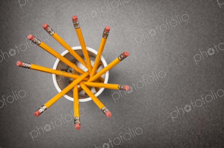 Yellow no.2 pencils in cup on desk in business office or school, view from above