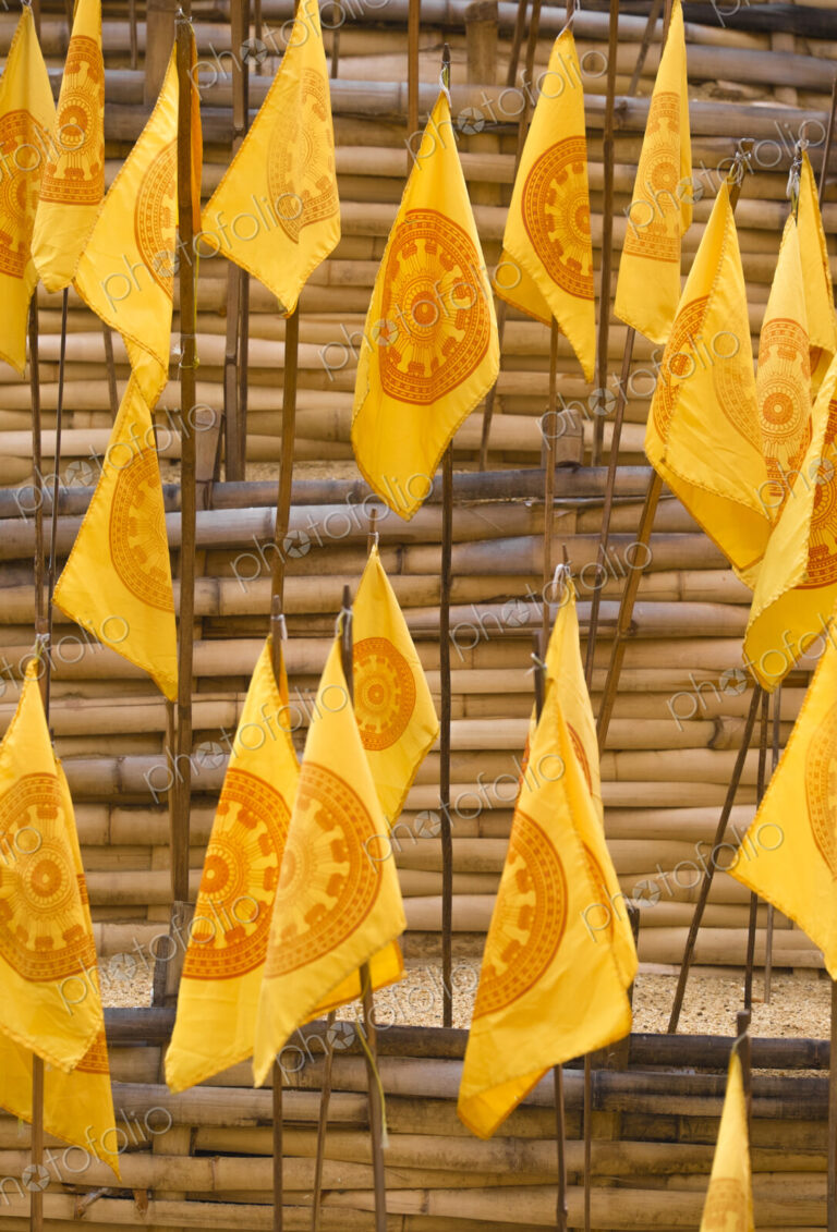Yellow prayer flags stuck in sand at a wat temple.