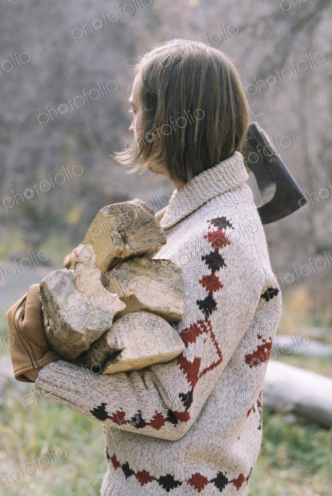 Young blond man carrying firewood.