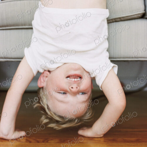 Young boy doing a handstand in front of a sofa. Young boy doing a handstand in front of a sofa.