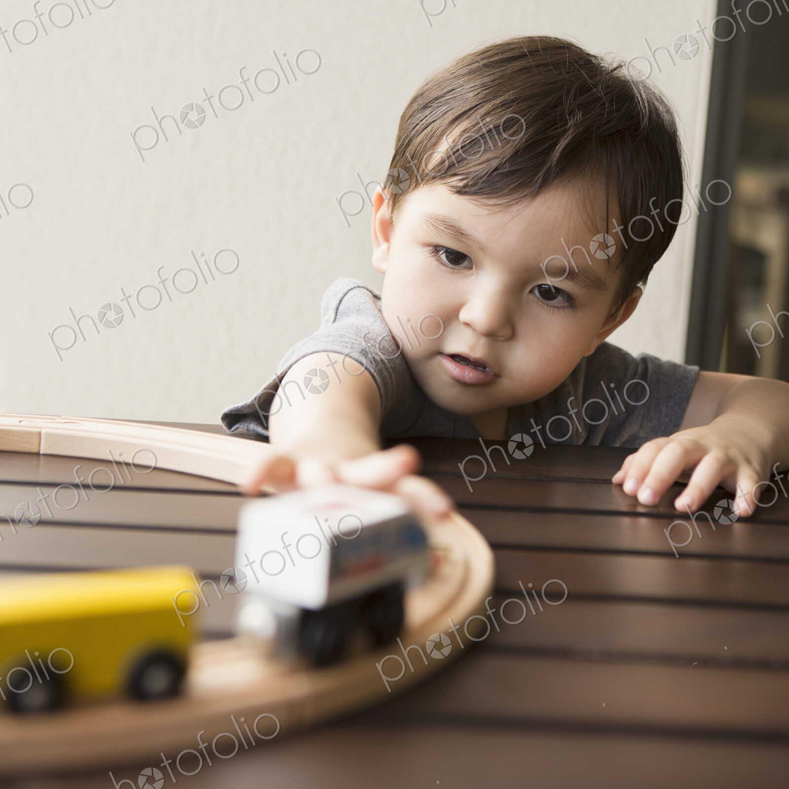 Young boy playing with a wooden train set.