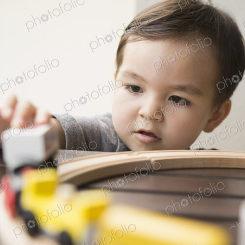 Young boy playing with a wooden train set. Young boy playing with a wooden train set.