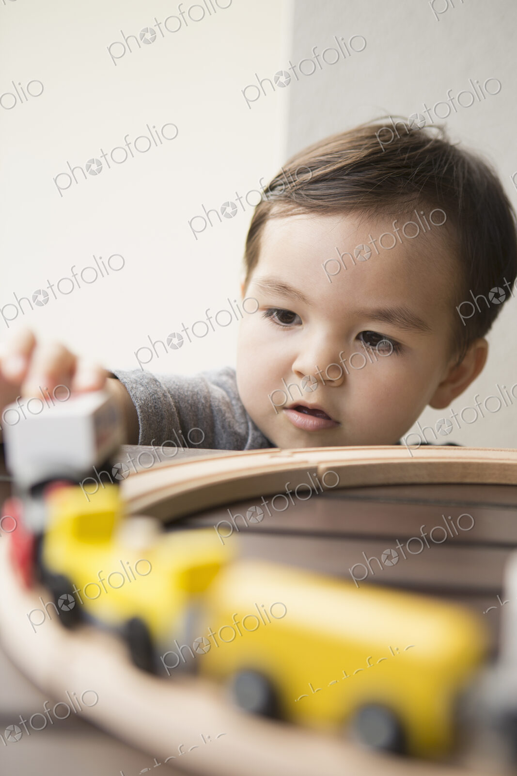 Young boy playing with a wooden train set.