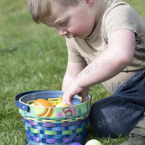 Young boy sitting on grass playing with basket of Easter eggs. Young boy sitting on grass playing with basket of Easter eggs.