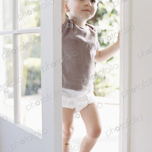 Young boy wearing T-Shirt and pants, opening a door. Young boy wearing T-Shirt and pants, opening a door.