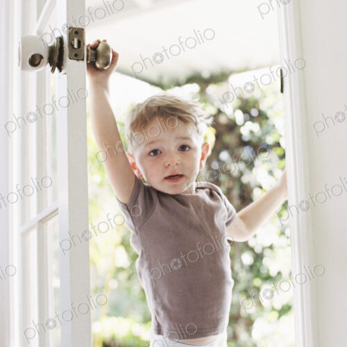 Young boy wearing T-Shirt and pants opening a door. Young boy wearing T-Shirt and pants opening a door.