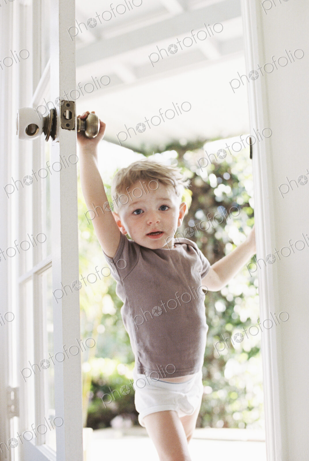 Young boy wearing T-Shirt and pants opening a door.