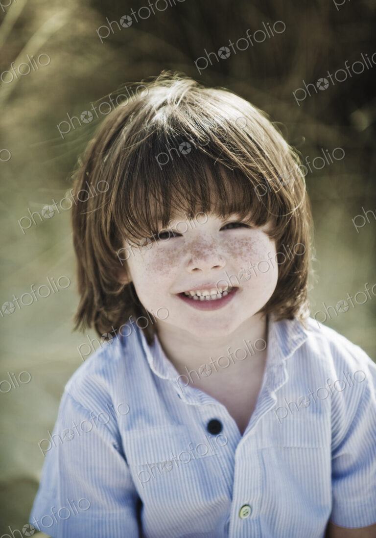 Young boy with brown hair and freckles, wearing blue shirt.