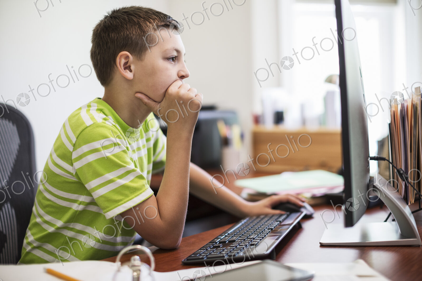 Young caucasian boy at work on a desktop computer system.