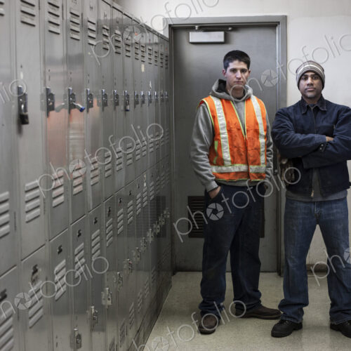 Young caucasian man and a black man factory woker standing next to lockers in a…