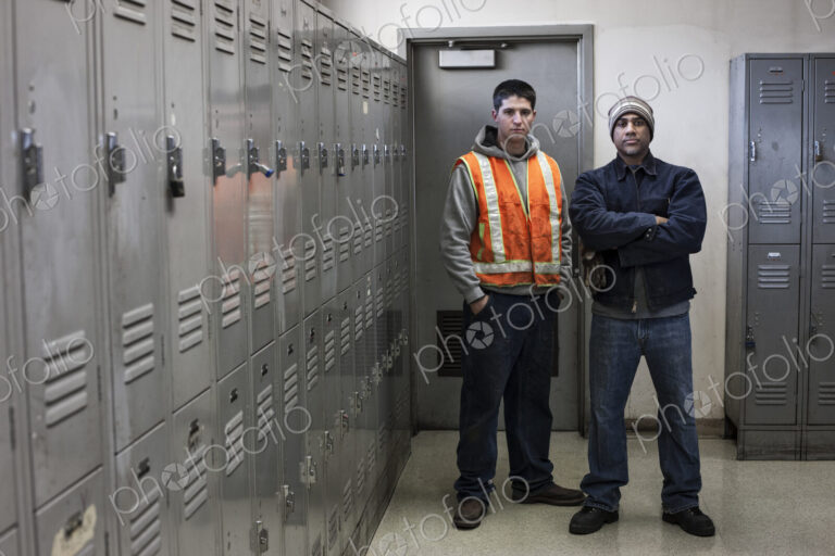 Young caucasian man and a black man factory woker standing next to lockers in a…