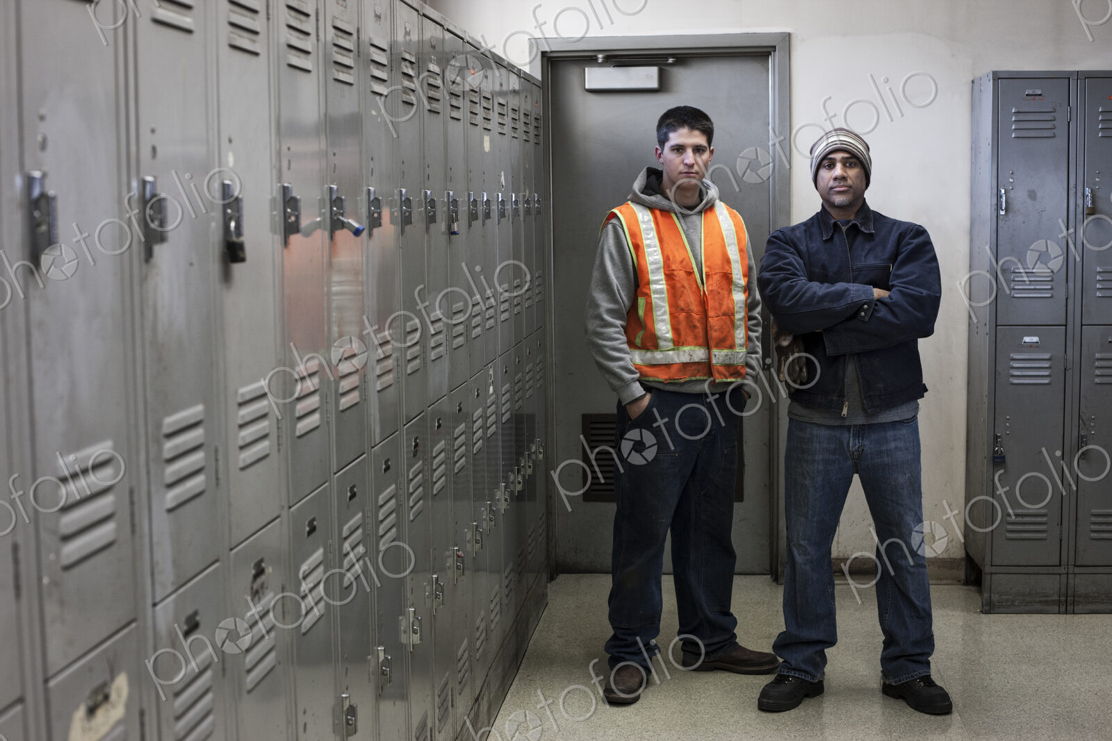 Young caucasian man and a black man factory woker standing next to lockers in a…