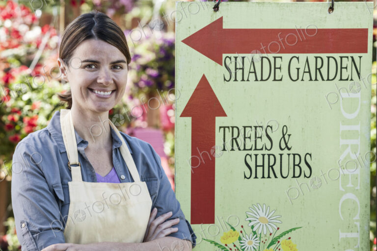 Young caucasian woman employee of a garden center nursery standing by an information sign.