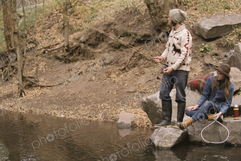Young couple in a forest, fishing in a river.