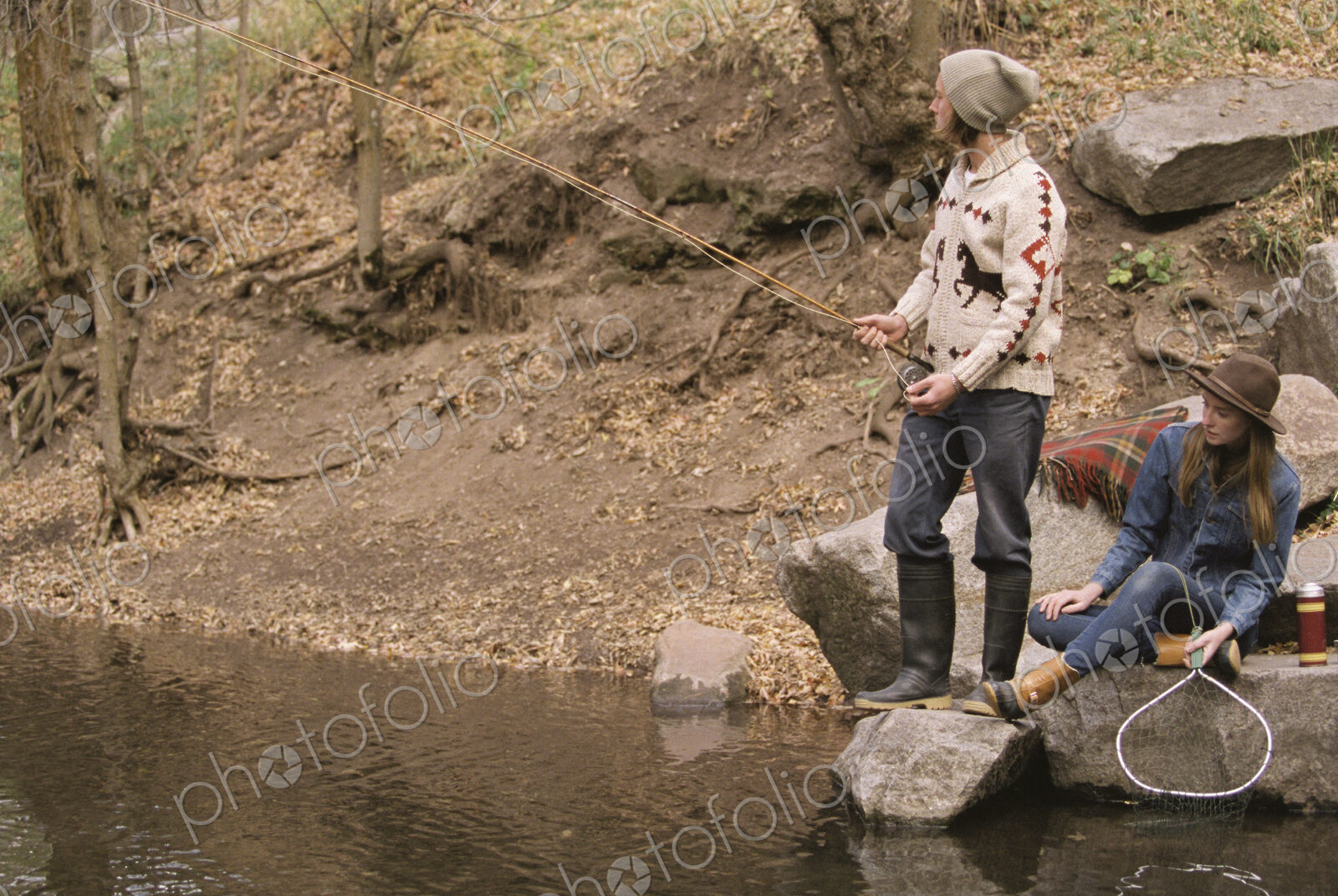 Young couple in a forest, fishing in a river.