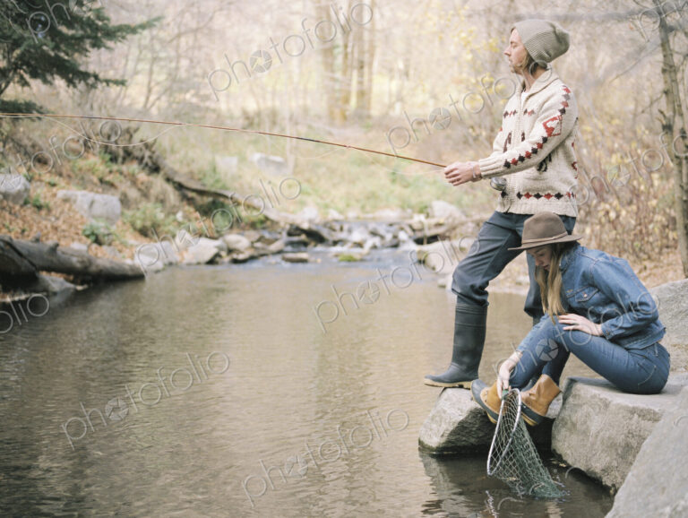 Young couple in a forest, fishing in a river.