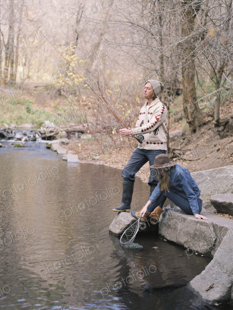 Young couple in a forest, fishing in a river.