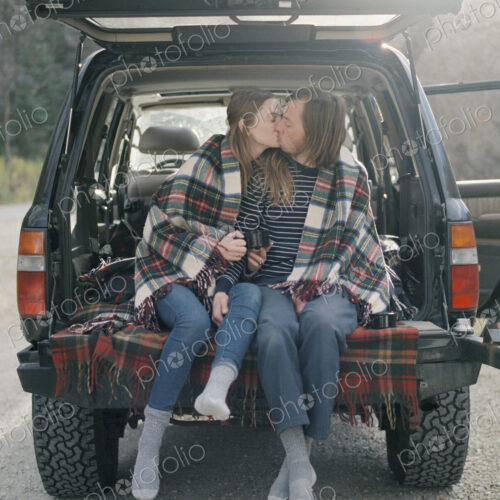 Young couple sitting in the back of their car, kissing. Young couple sitting in the back of their car, kissing.