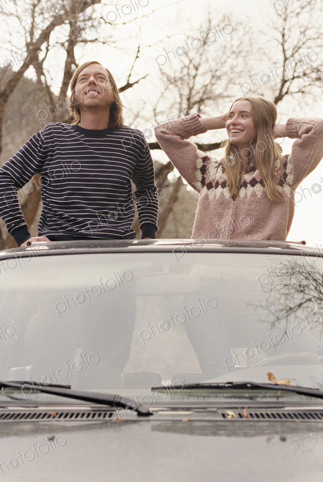 Young couple standing in their car, looking through sunroof.