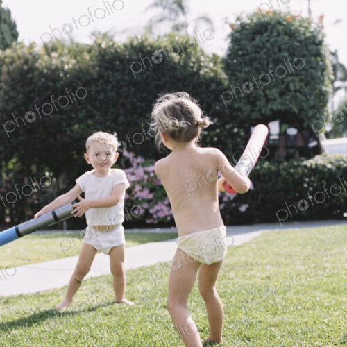 Young girl and young boy, two children wearing T-Shirt and shorts playing in a garden. Young girl and young boy, two children wearing T-Shirt and shorts playing in a garden.