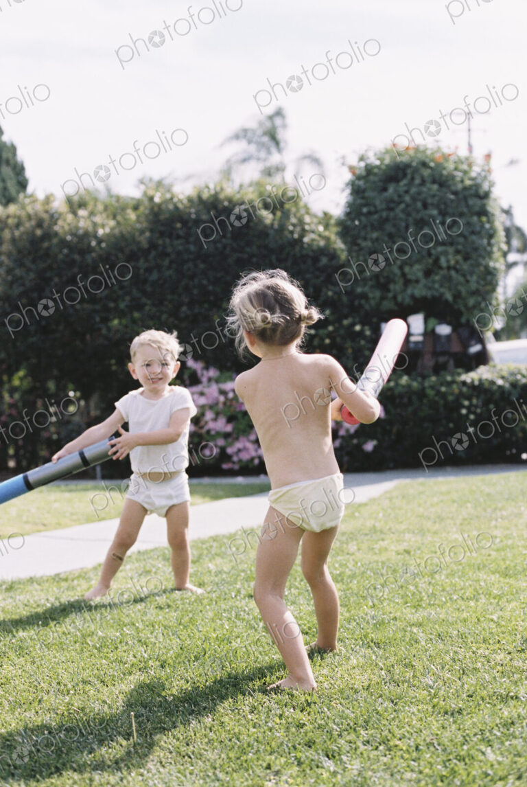 Young girl and young boy, two children wearing T-Shirt and shorts playing in a garden.