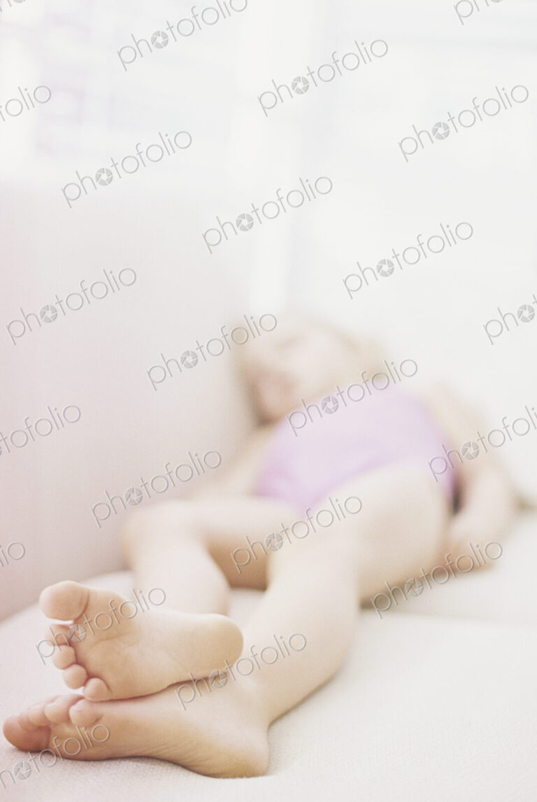 Young girl in a pink swimsuit lying on a sofa, taking a nap.