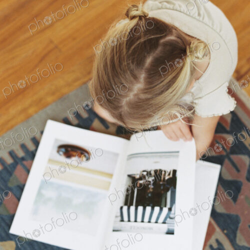 Young girl sitting on the floor, reading a book, view from above Young girl sitting on the floor, reading a book, view from above