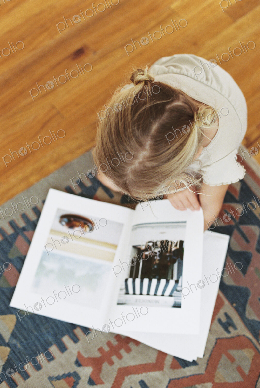 Young girl sitting on the floor, reading a book, view from above