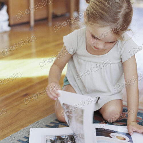 Young girl sitting on the floor, reading a lifestyle magazine. Young girl sitting on the floor, reading a lifestyle magazine.