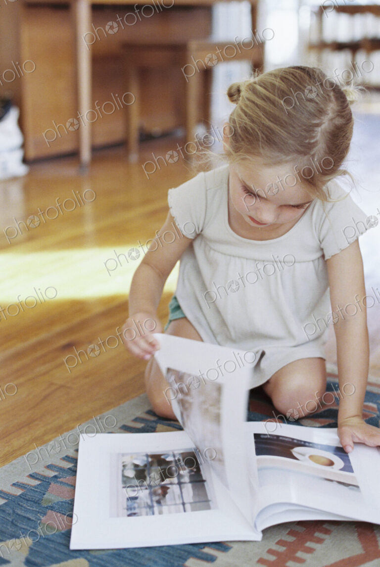 Young girl sitting on the floor, reading a lifestyle magazine.