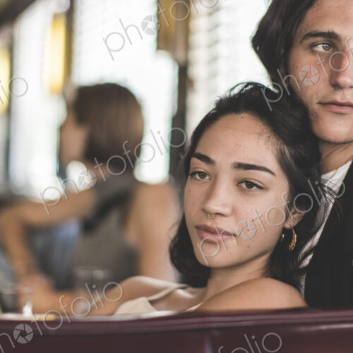 Young man and woman sitting in a booth in a diner close together, relaxed, a woman in… Young man and woman sitting in a booth in a diner close together, relaxed, a woman in…
