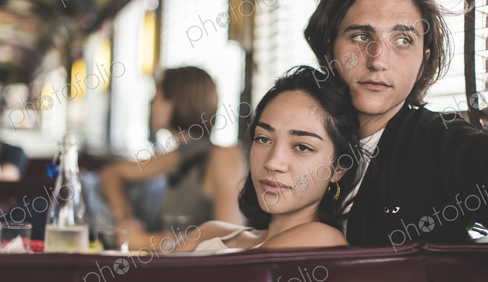 Young man and woman sitting in a booth in a diner close together, relaxed, a woman in…