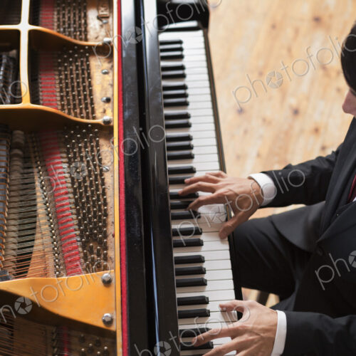 Young man playing on a grand piano in a rehearsal studio. Young man playing on a grand piano in a rehearsal studio.