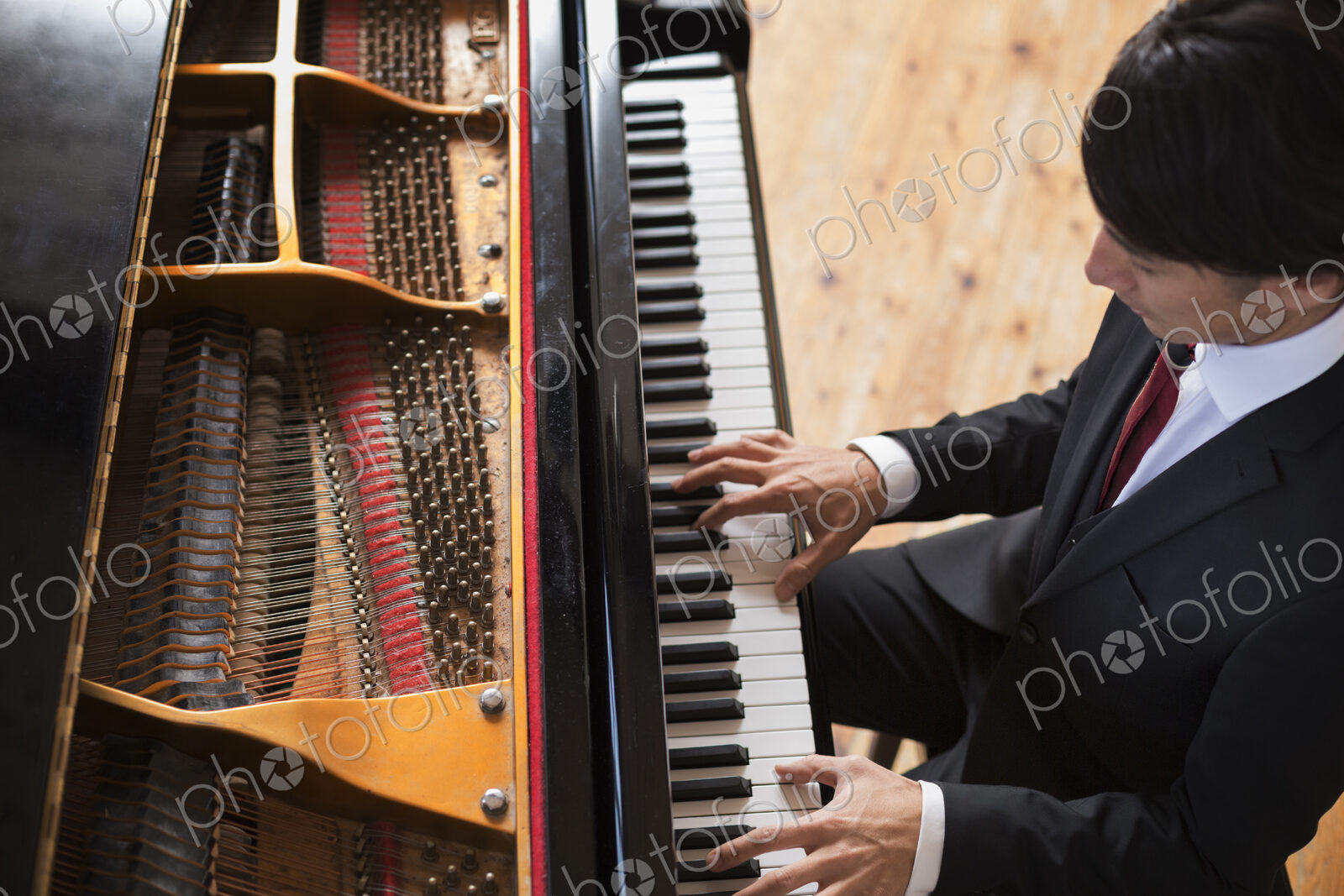 Young man playing on a grand piano in a rehearsal studio.