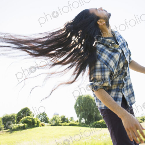 Young man shaking out his long black hair, tilting his head