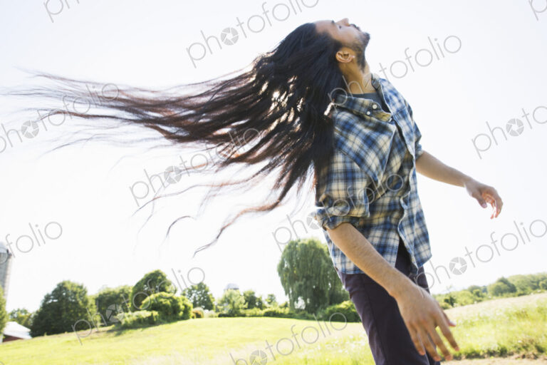 Young man shaking out his long black hair, tilting his head